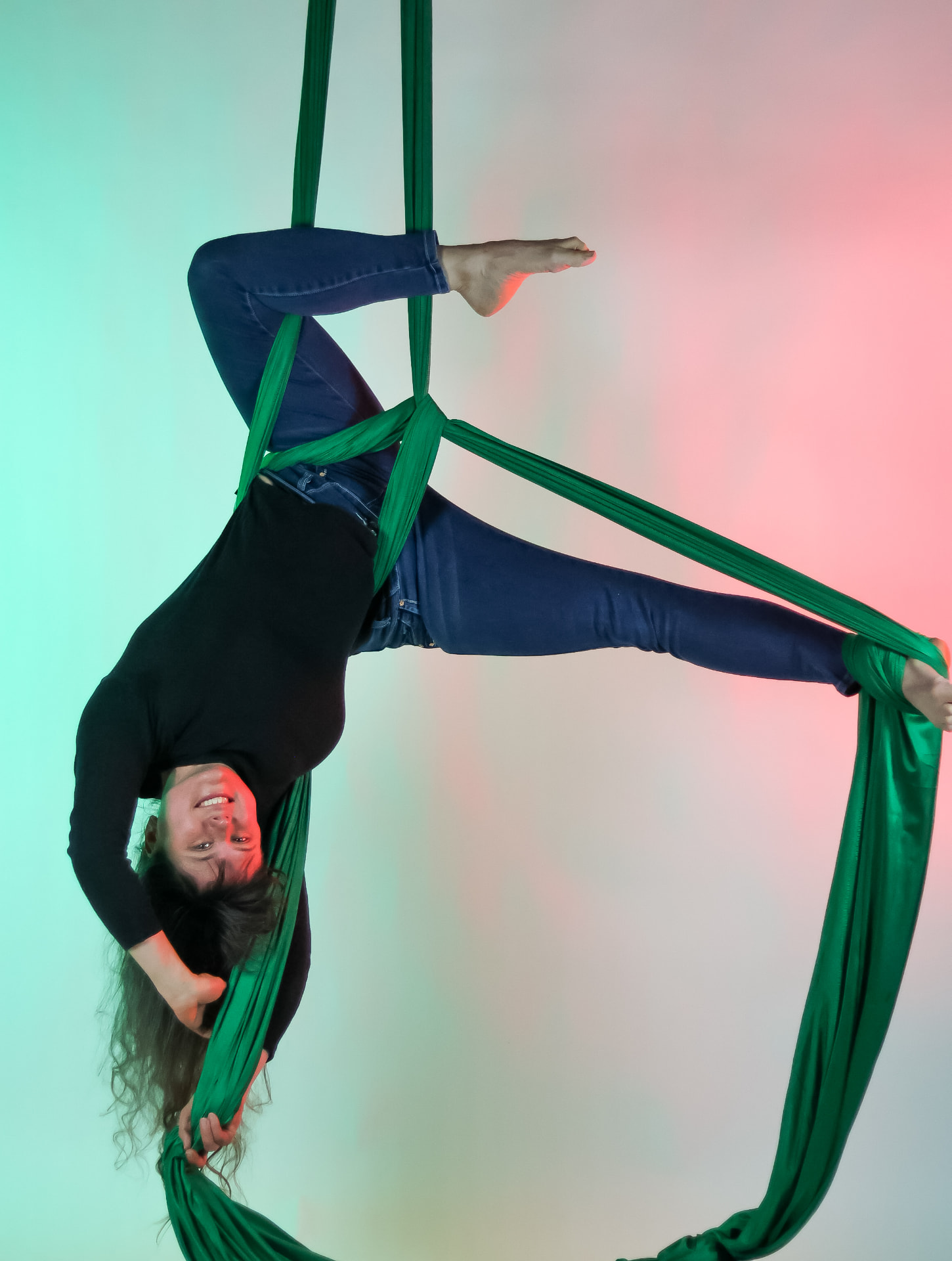 Aerialist inverting on green aerial silks at Flexibility in Flight